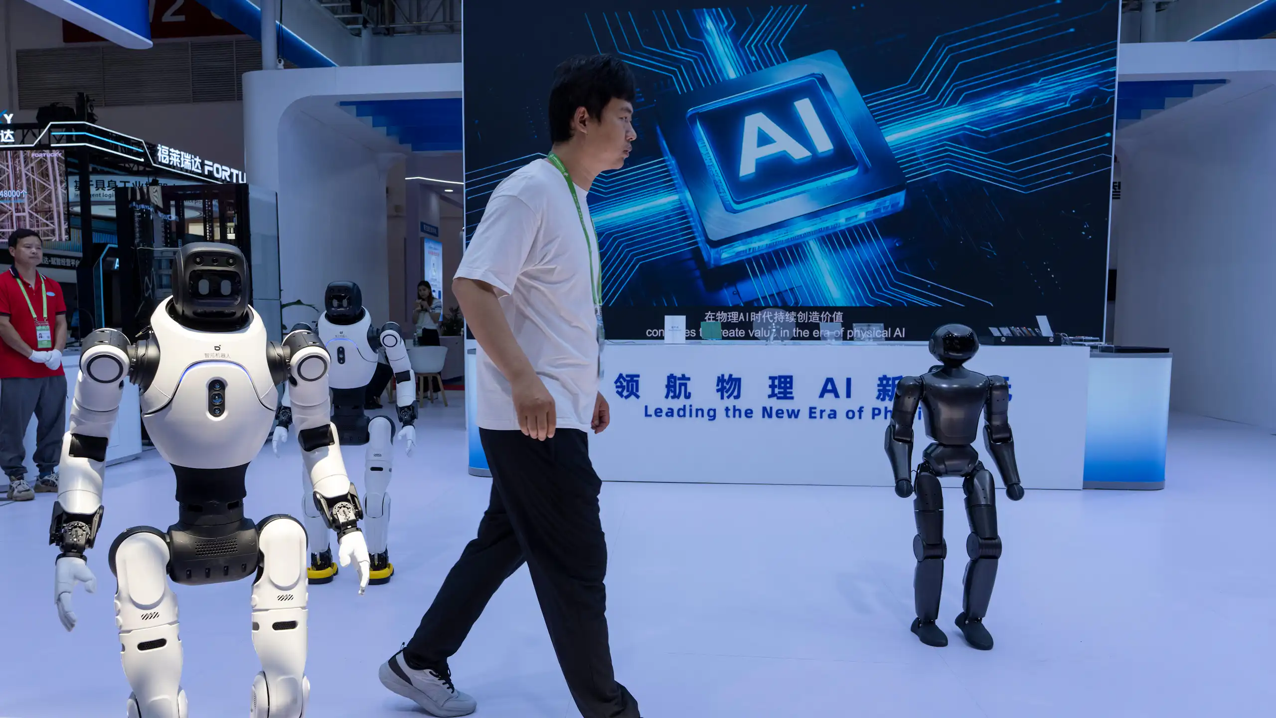 Un homme marche entre des robots humanoïdes, avec un panneau publicitaire faisant la promotion de l'IA en arrière-plan.