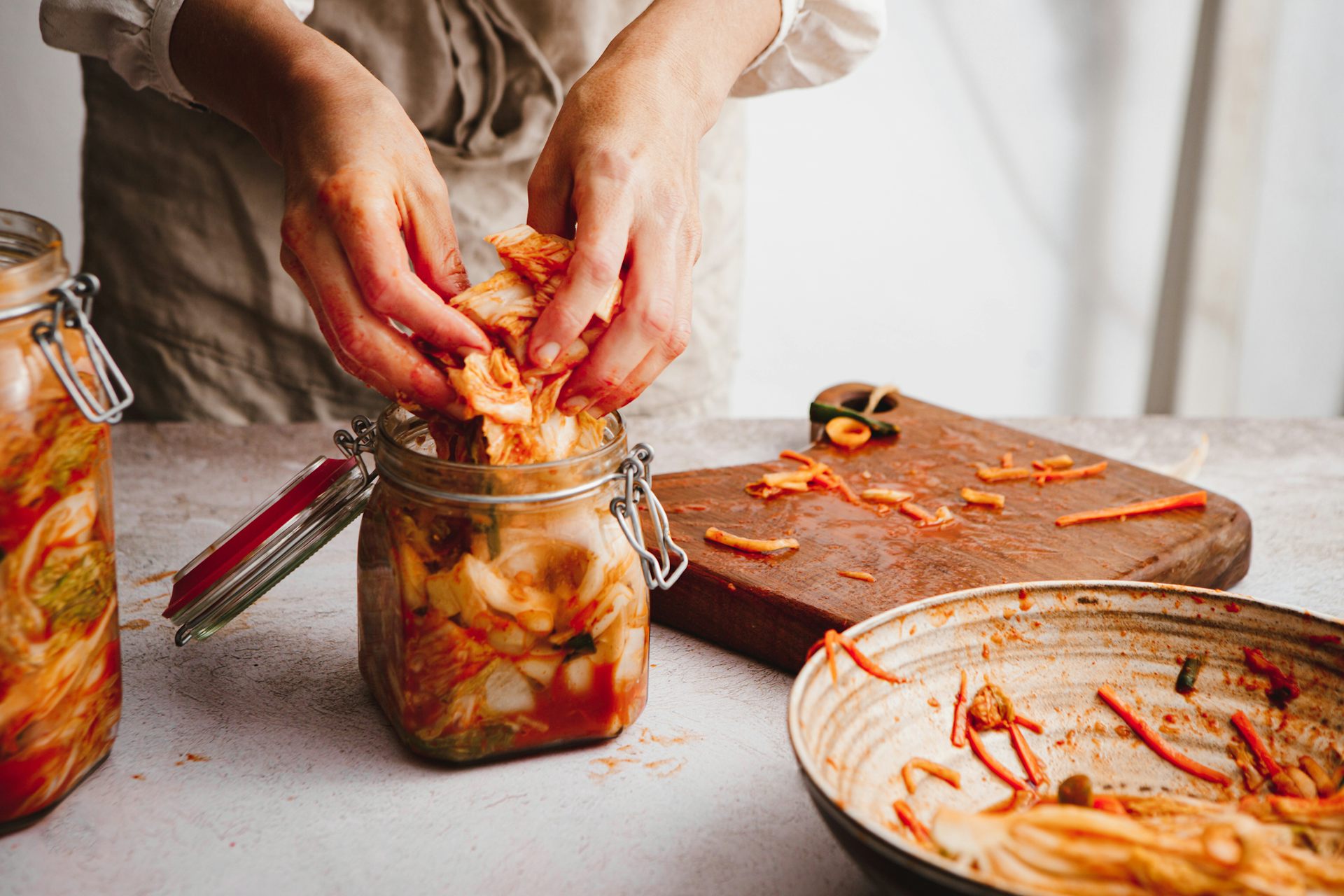 Close-up of a person filling a jar with homemade kimchi