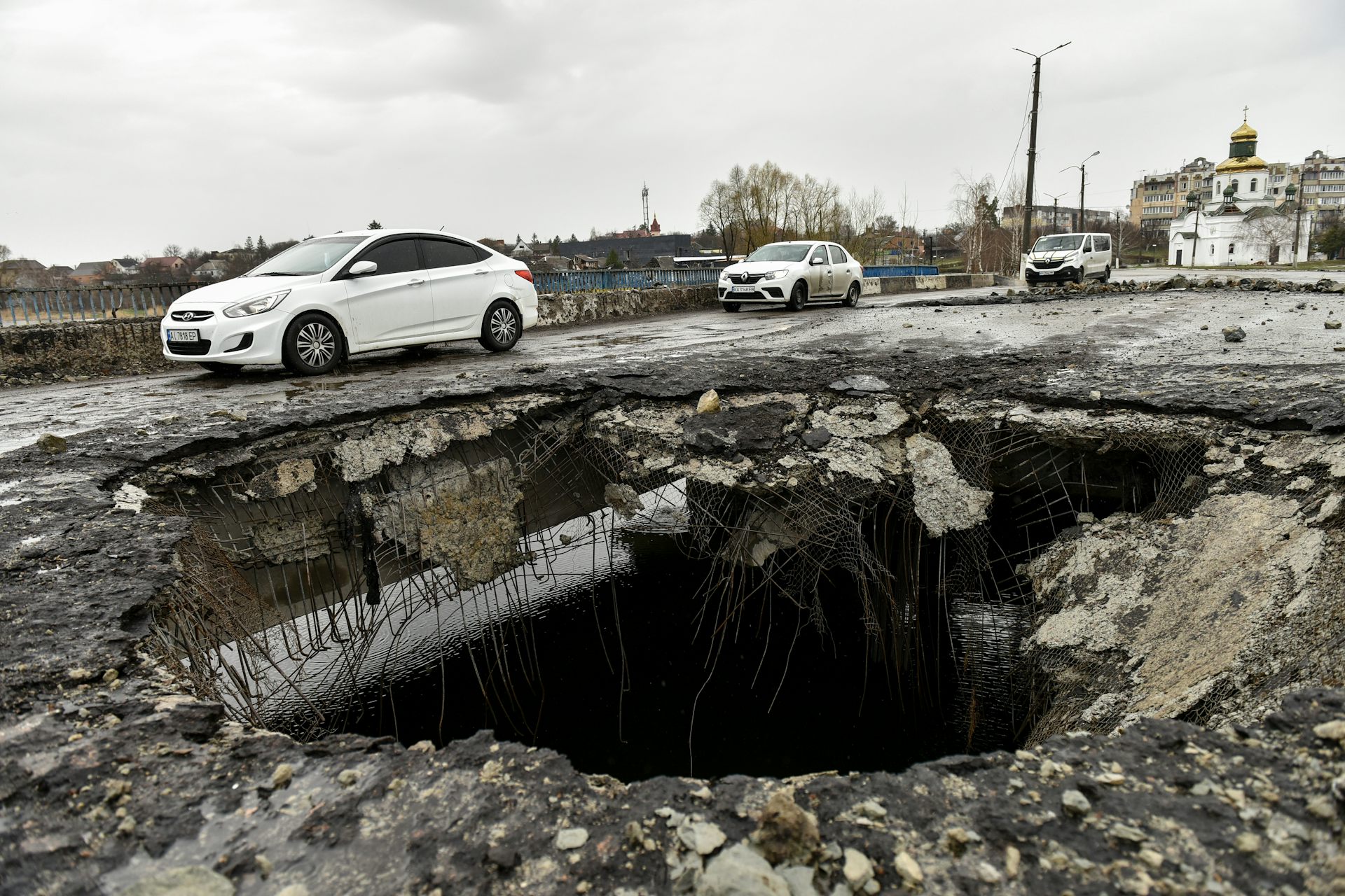 A shell crater on a damaged bridge in Makariv.