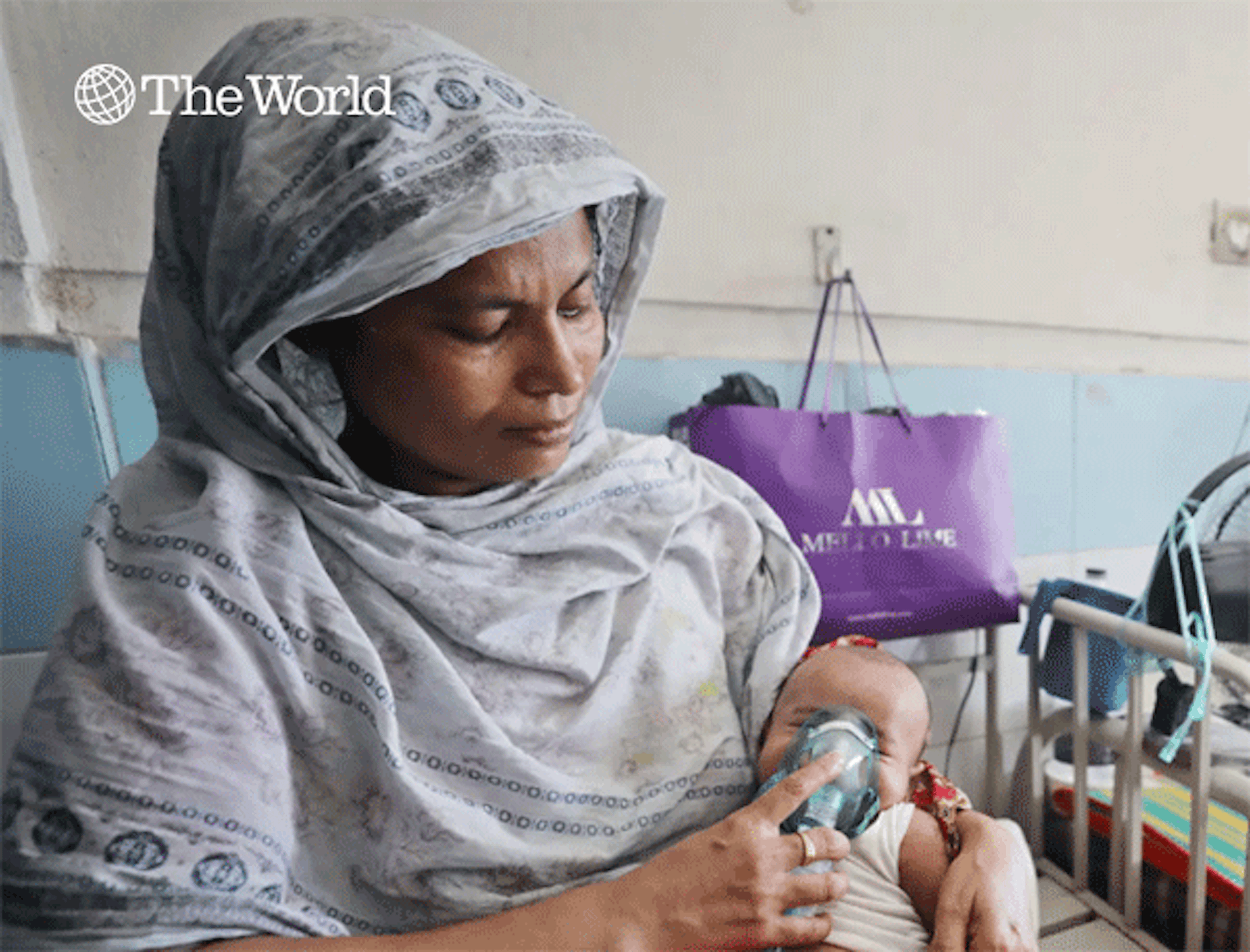 woman in white protective suit holds a respirator to a baby's face