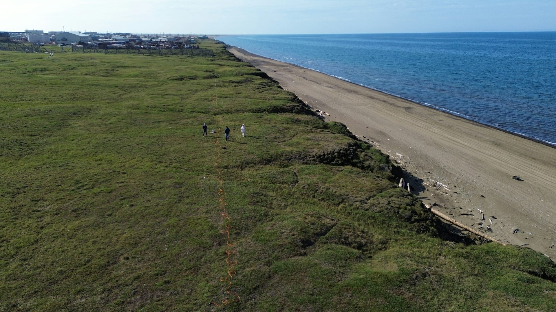 Scientists on a plain near the coast with a line on the ground.