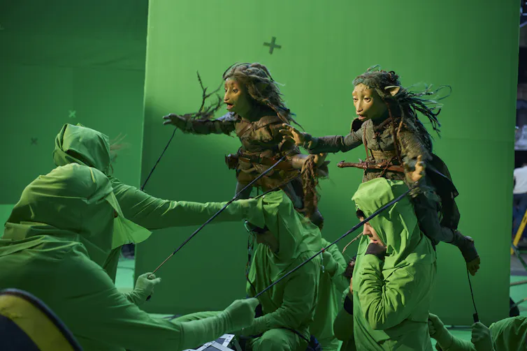 Two puppets performed by three people in green screen suits.