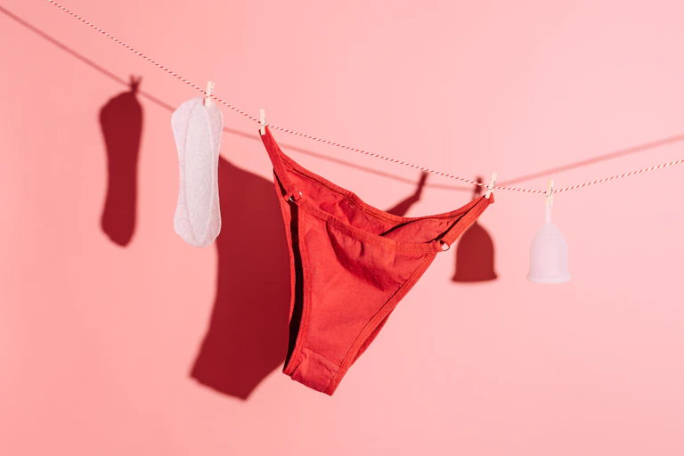 Underwear and socks hanging on clothesline on pink background, womens health concept - stock photo
