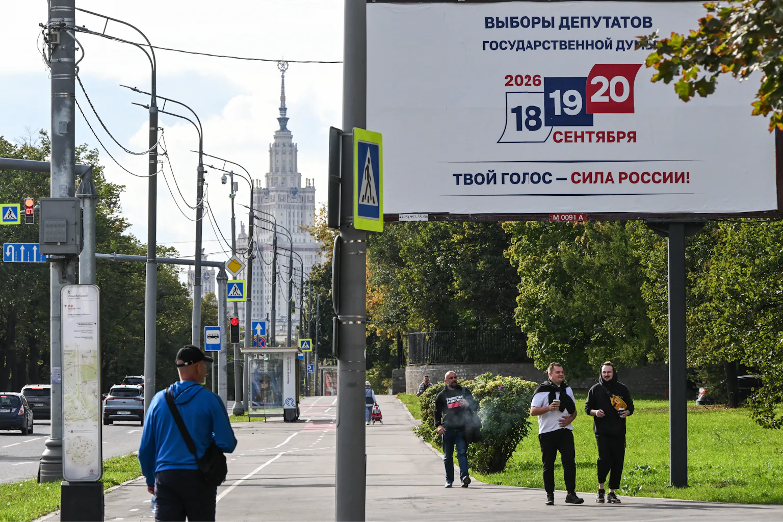 People walk past a large billboard with '18,19,20' written on it.