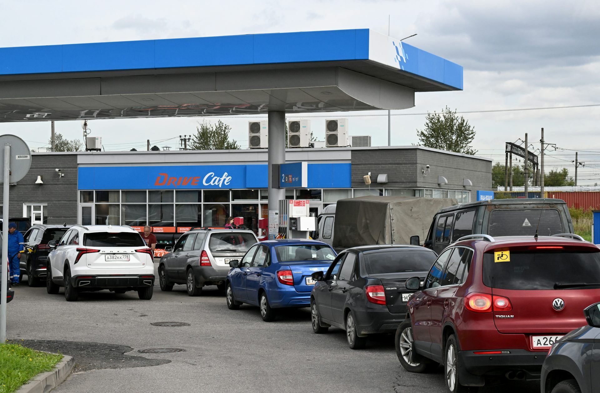 A long line of cars is seen outside a gas station.