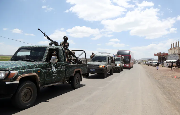A gun-mounted truck leads a convoy of vehicles.