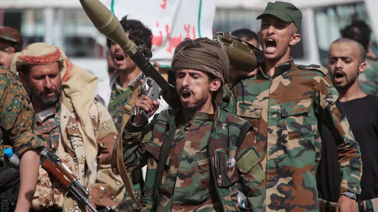 Men in military fatigues with weapons.
