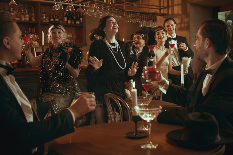 A retro party crowd laughing and celebrating with cocktails.