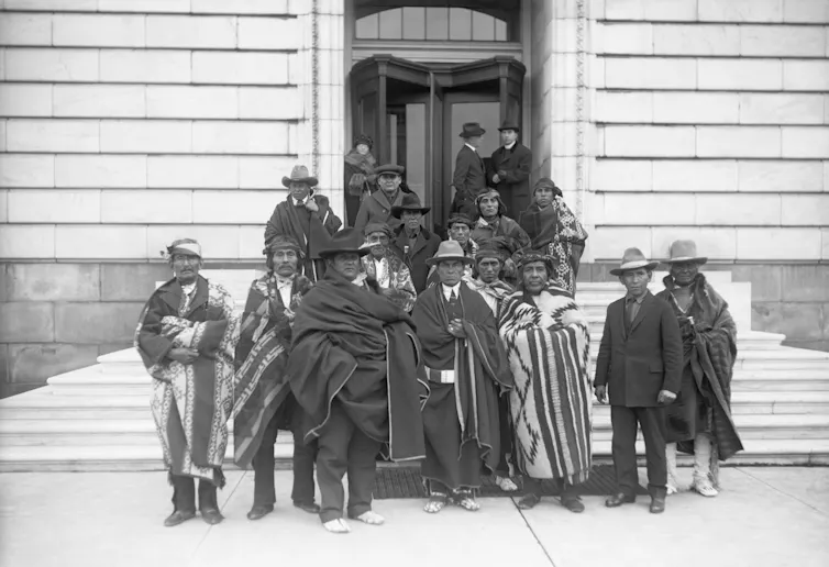 More than a dozen Indigenous people gather on steps for formal black and white photo