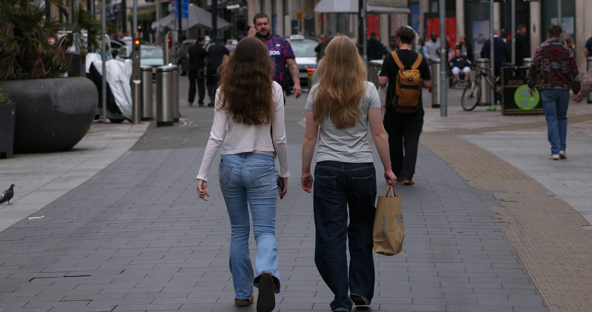 Two young women walking away on a pedestrian street in Cardiff