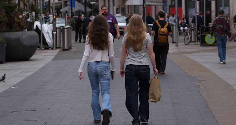 Two young women walking away on a pedestrian street in Cardiff