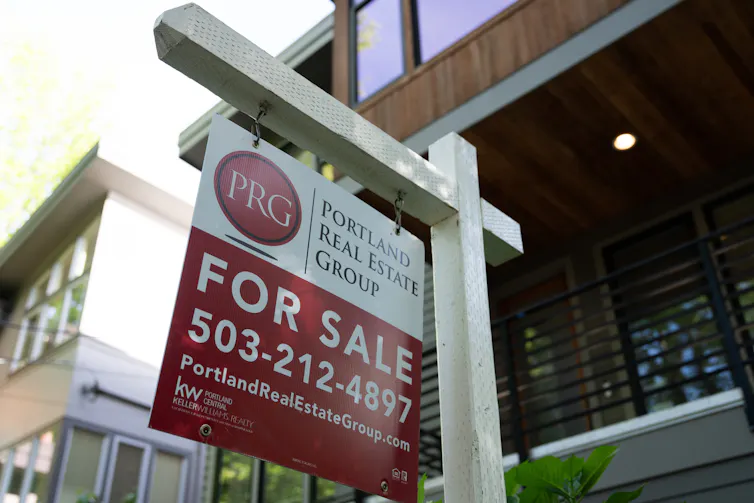 A red and white 'for sale' sign is displayed outside a home in Portland, Ore.
