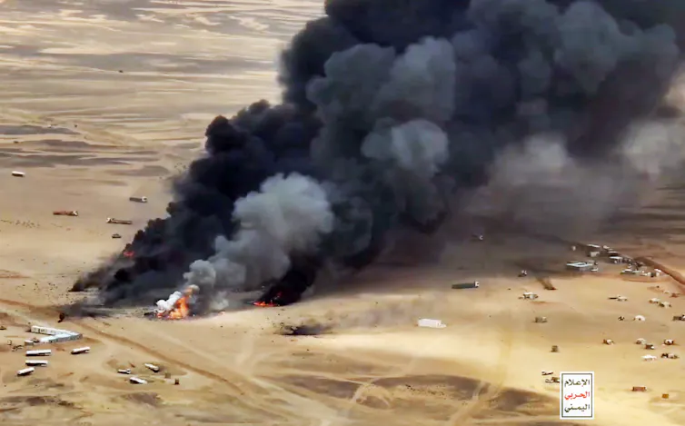 A black plume of sm okes rises from the desert.