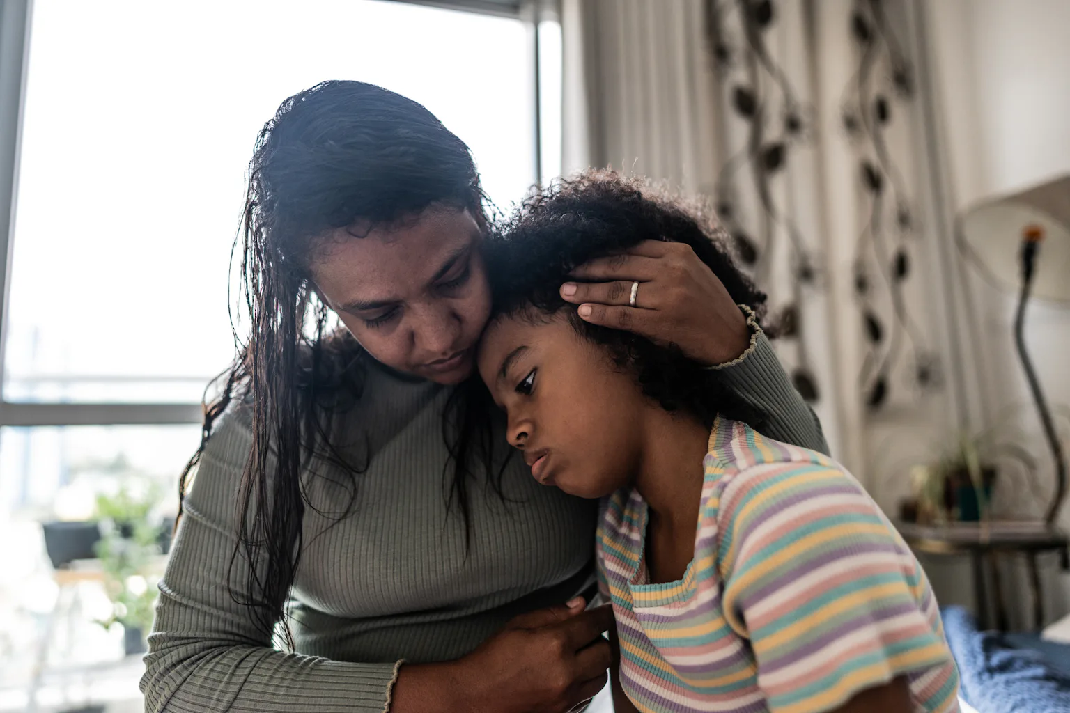 Parent holding child's head against chest with hand threaded through hair.