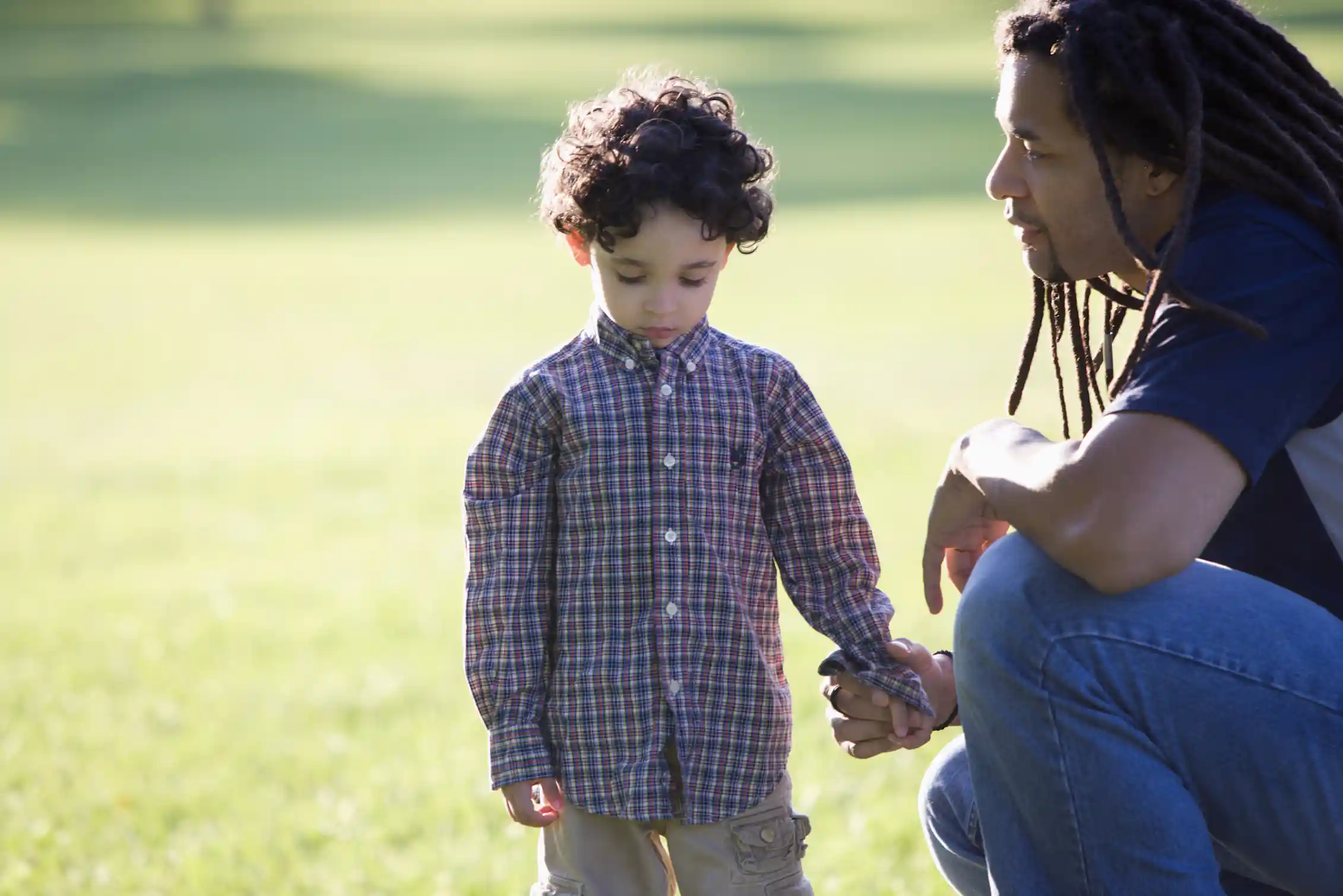 Father kneeling down holding hand of child outside