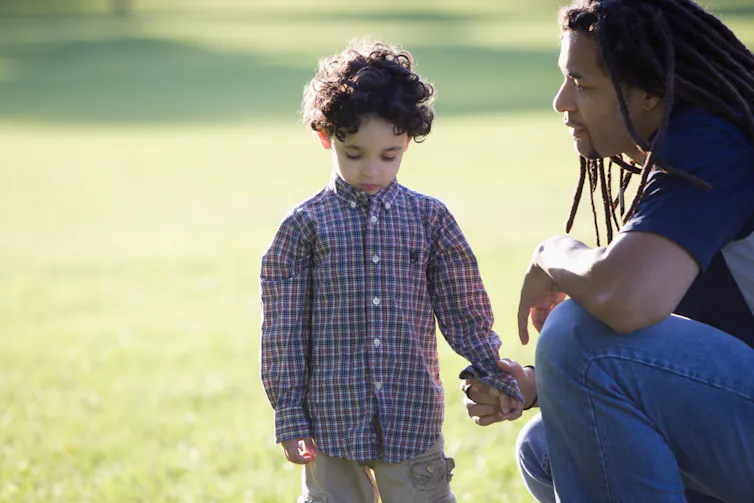 Father kneeling down holding hand of child outside