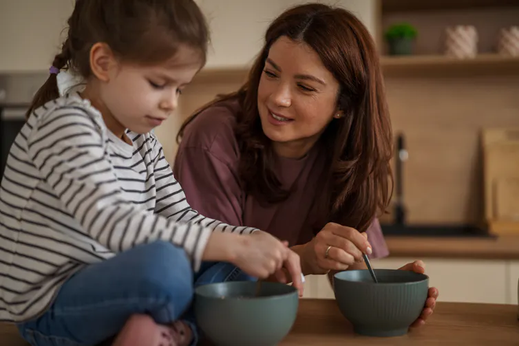 Parent and child talking over two bowls of food.