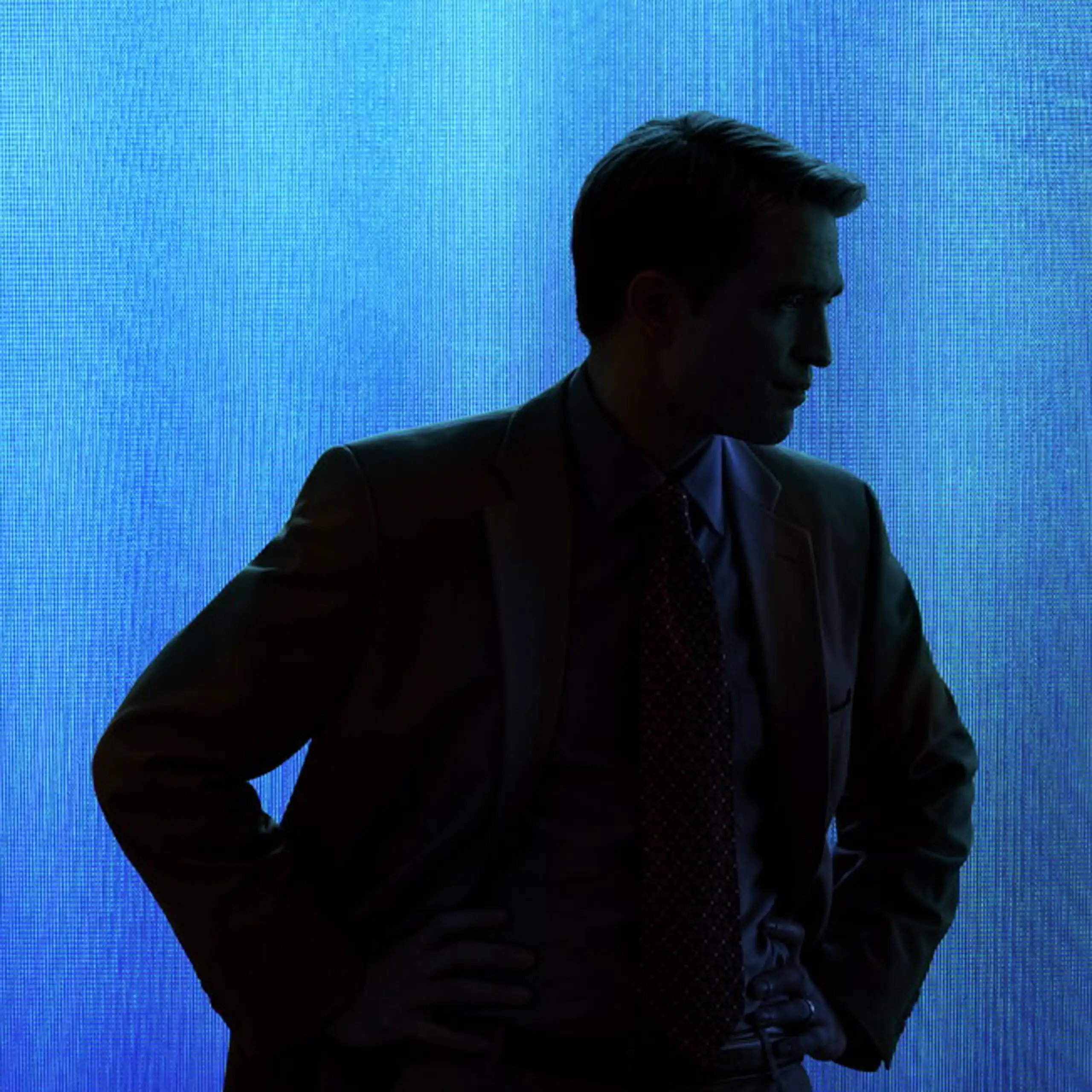 A silhouette of a young man with his hands on his hips against a blue backdrop.