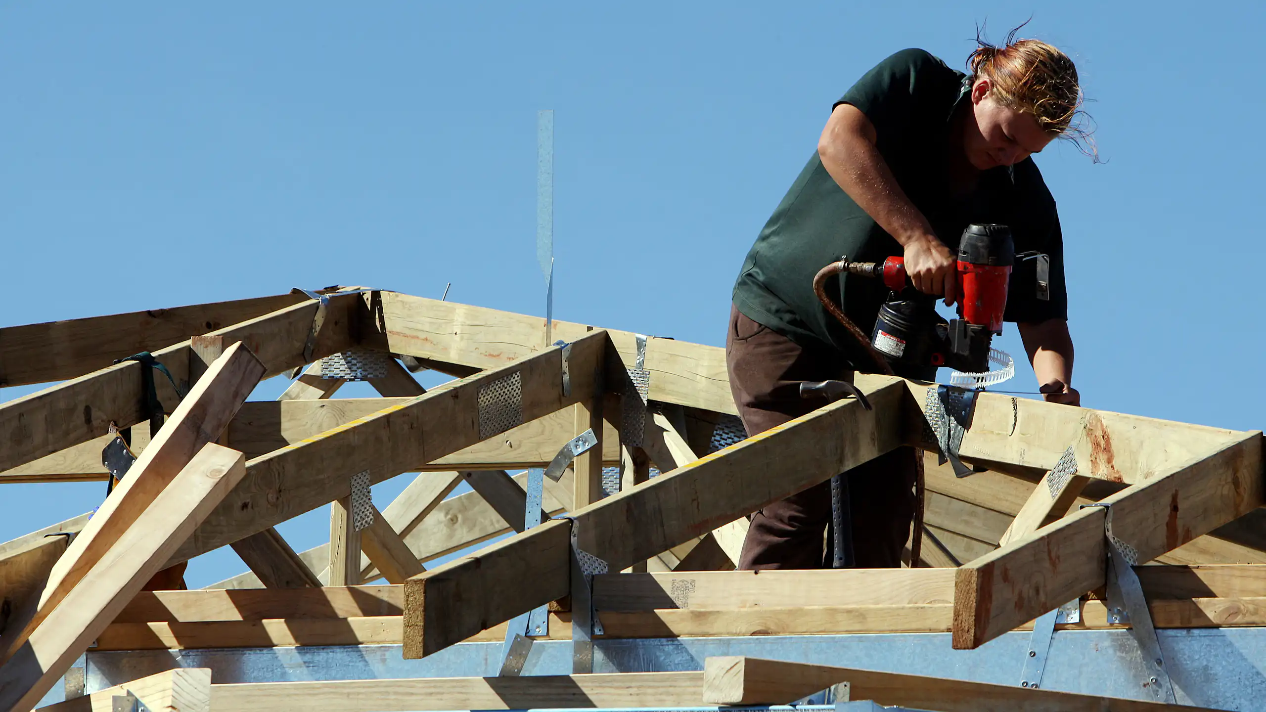 A female carpenter works on the roof of a new house construction a