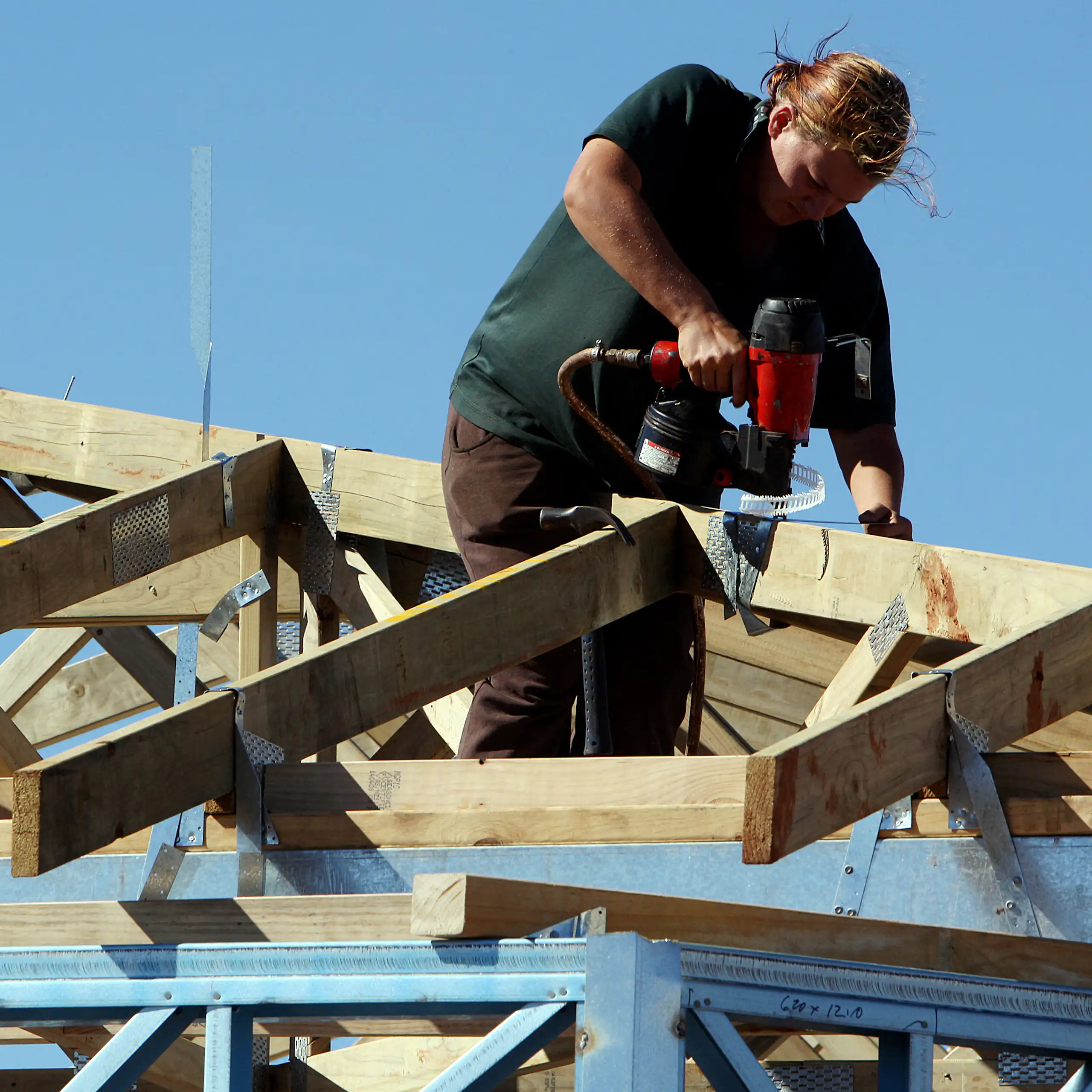 A female carpenter works on the roof of a new house construction a