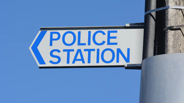A police road sign against blue sky.