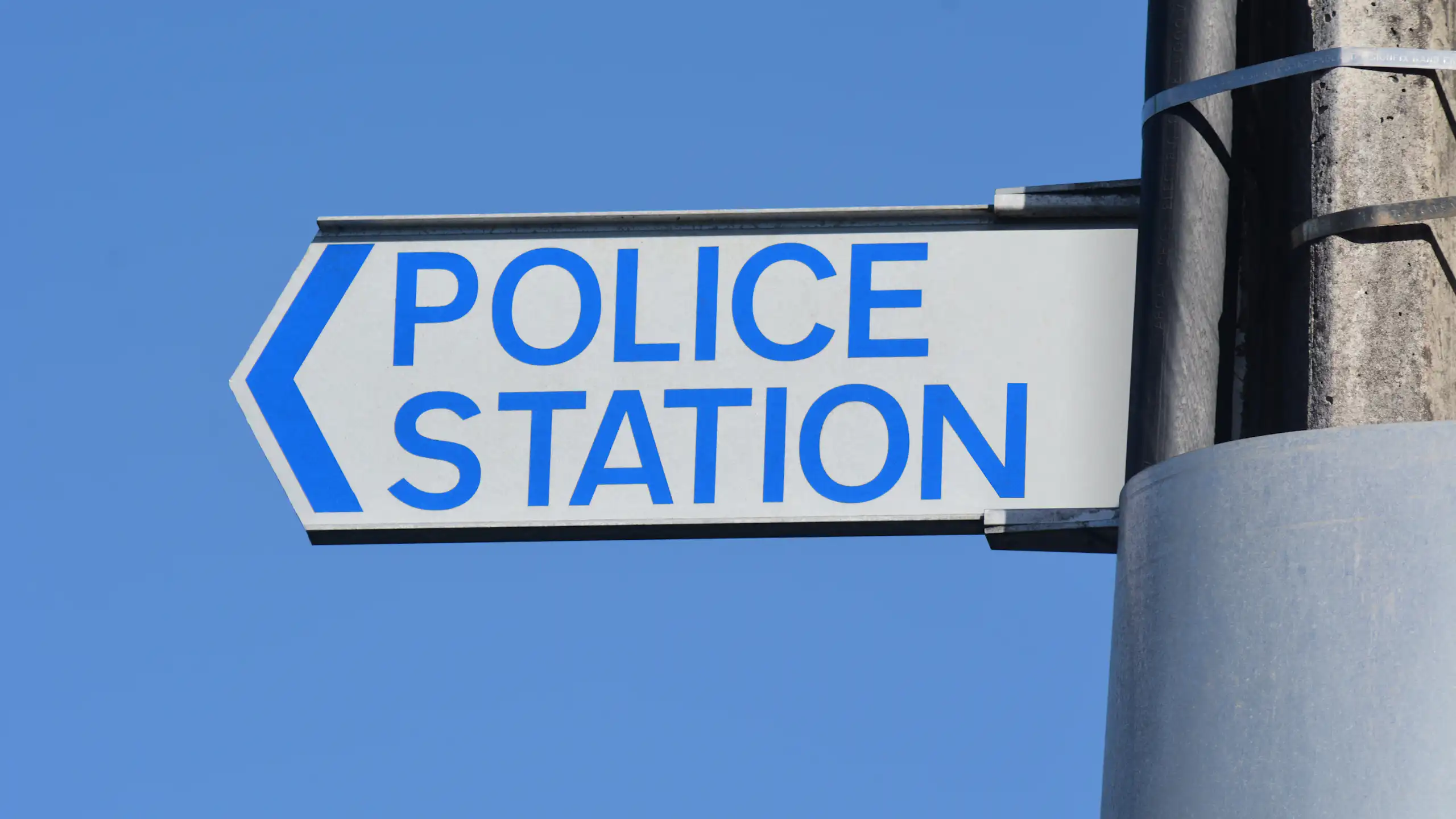A police road sign against blue sky.
