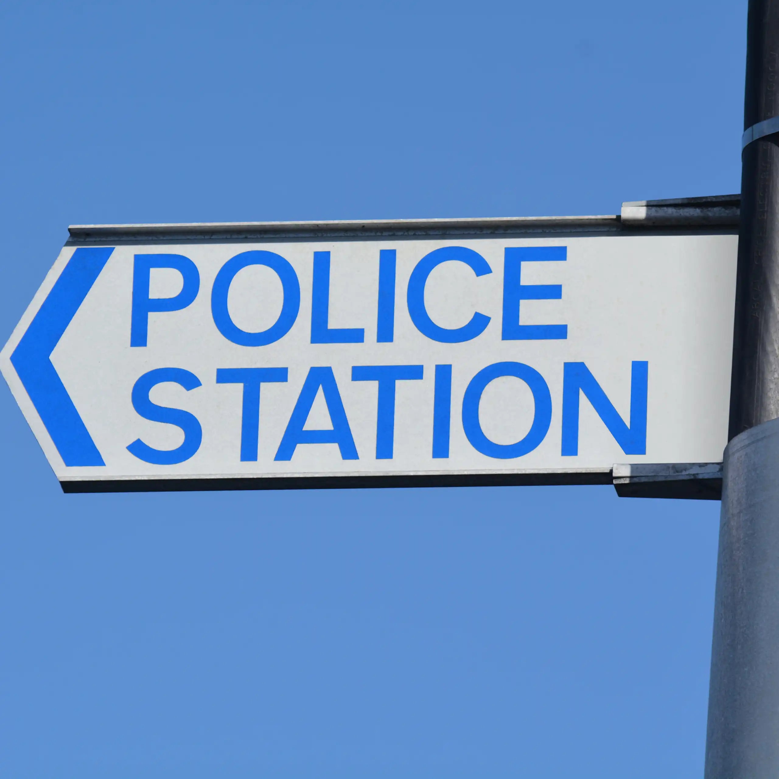 A police road sign against blue sky.