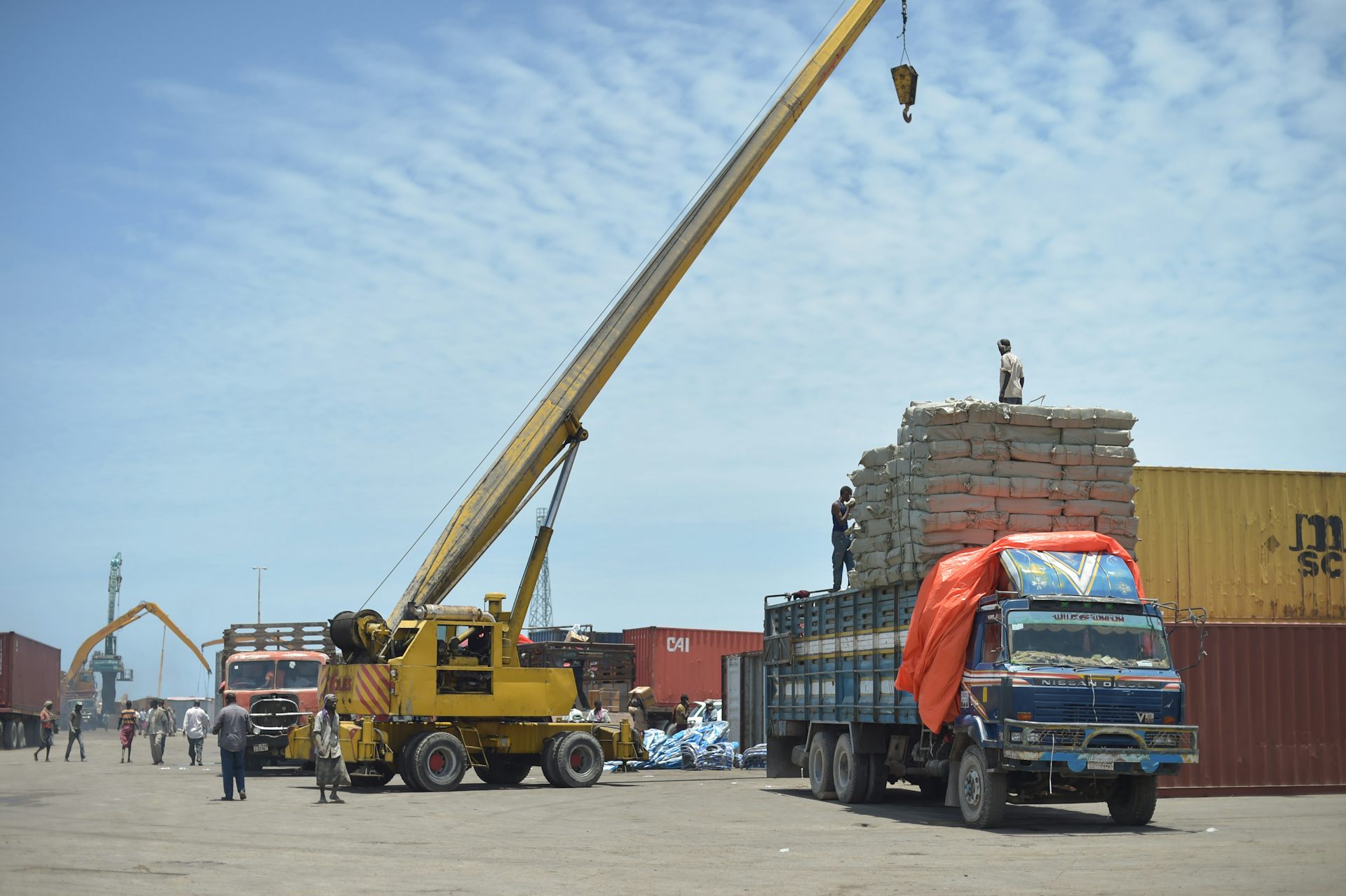 A mobile crane loads goods onto a truck