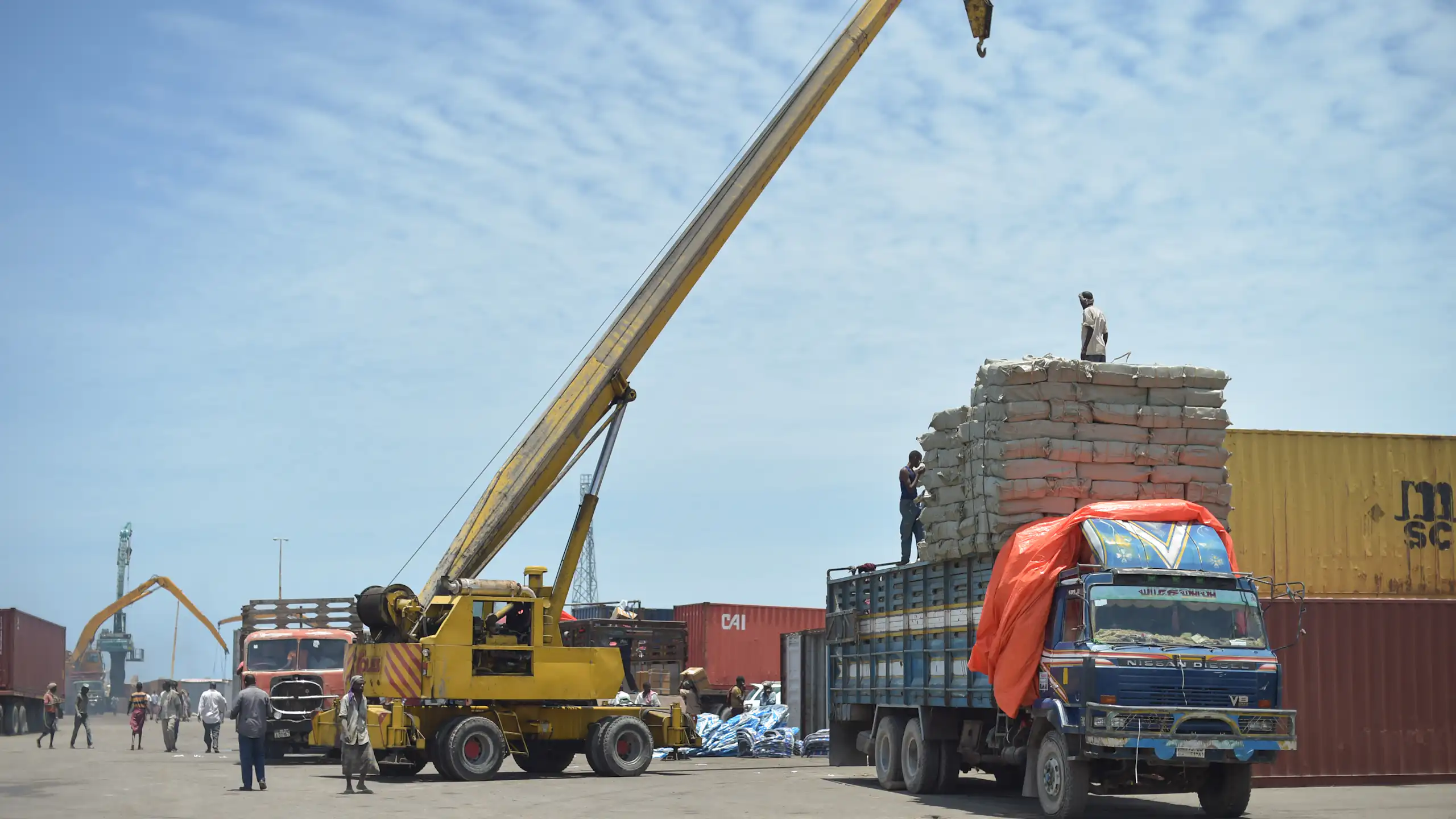 A mobile crane loads goods onto a truck