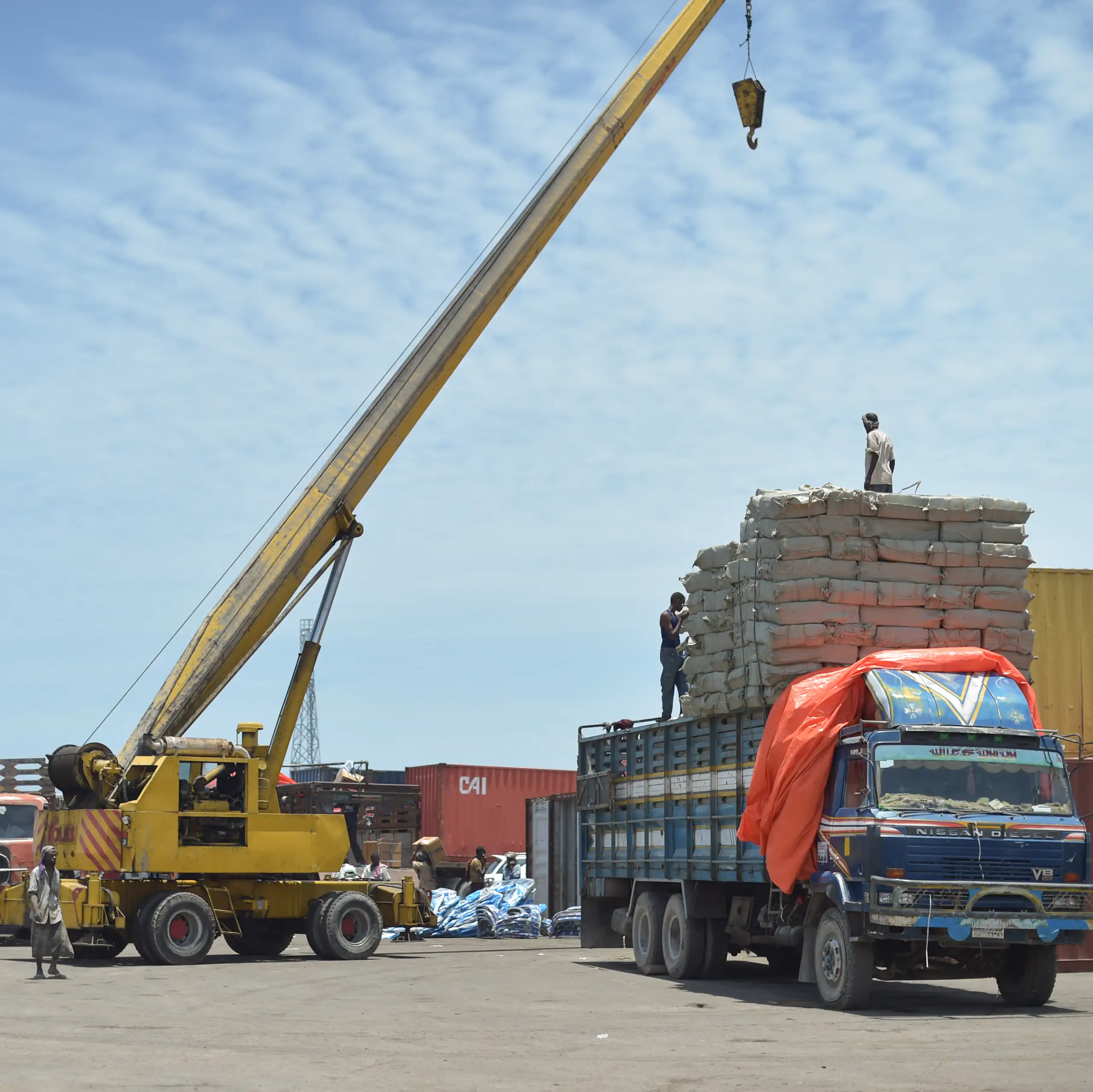 A mobile crane loads goods onto a truck
