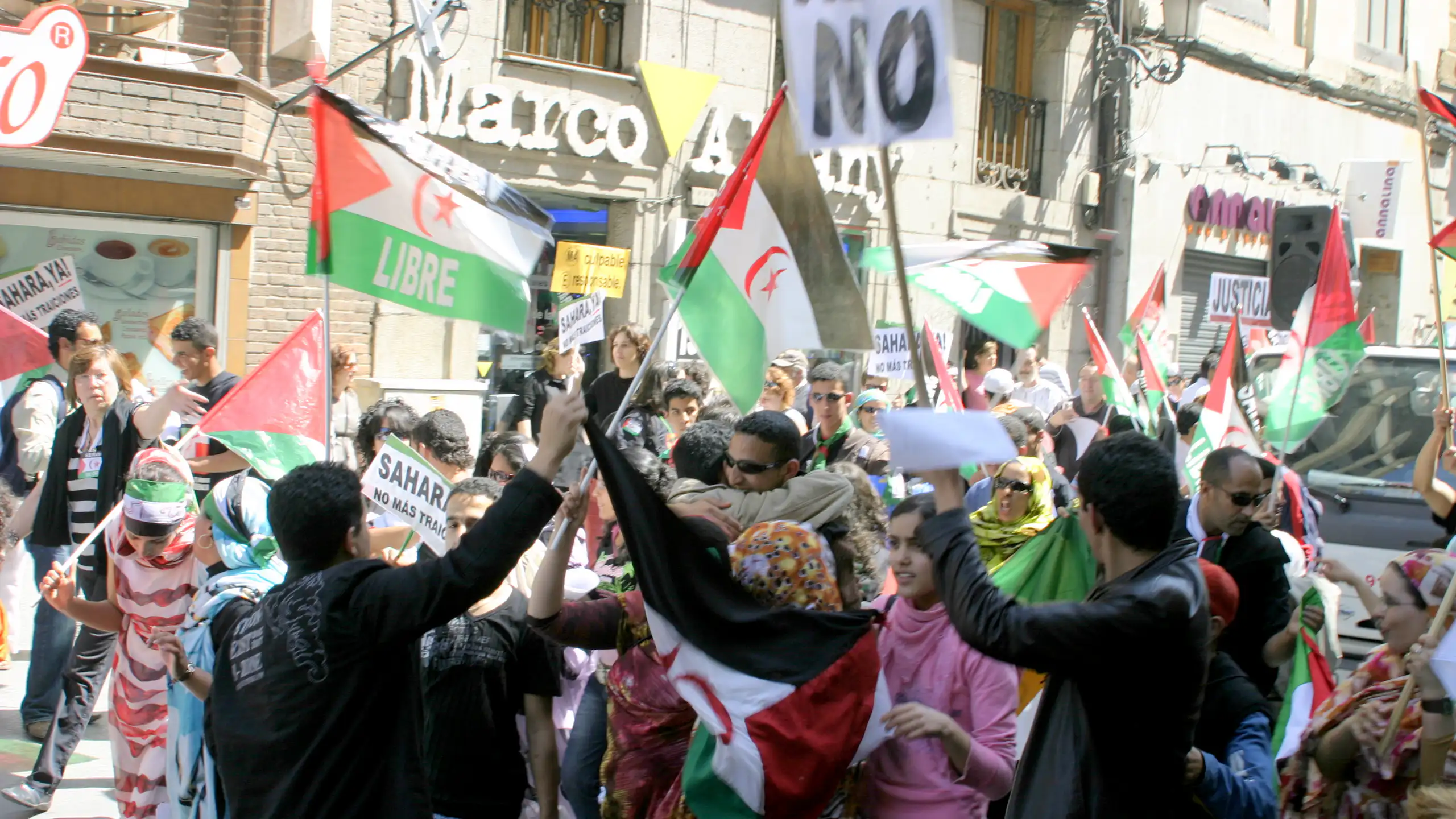 A group of men and women holding up placards and flags on a busy street