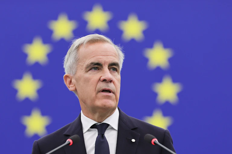 Mark Carney delivers a speech in front an EU flag.