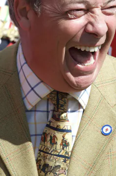 A laughing man wearing a Bayeux tapestry tie.