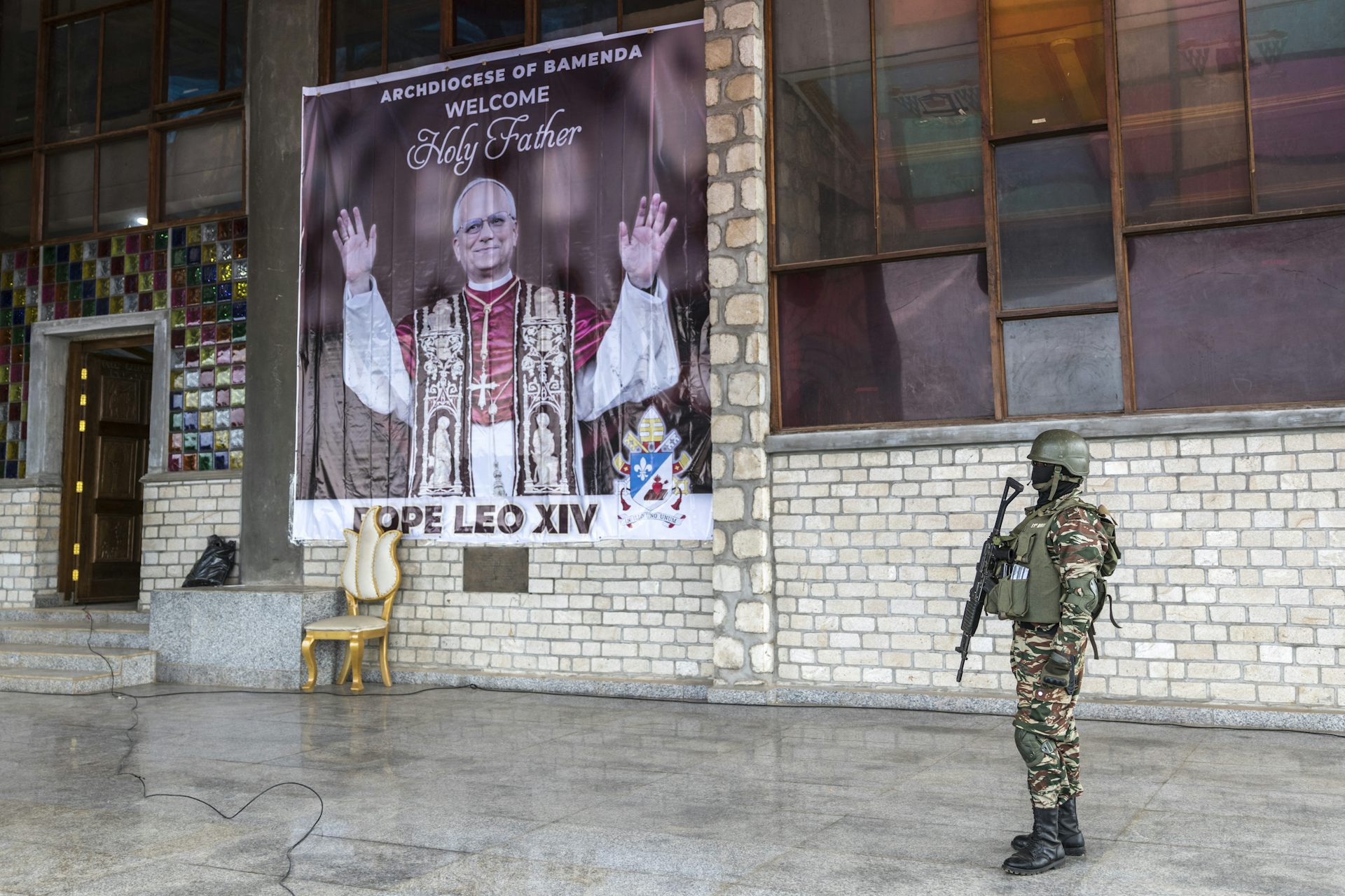 Affiche de Léon XIV, un soldat camerounais en armes se tient devant.