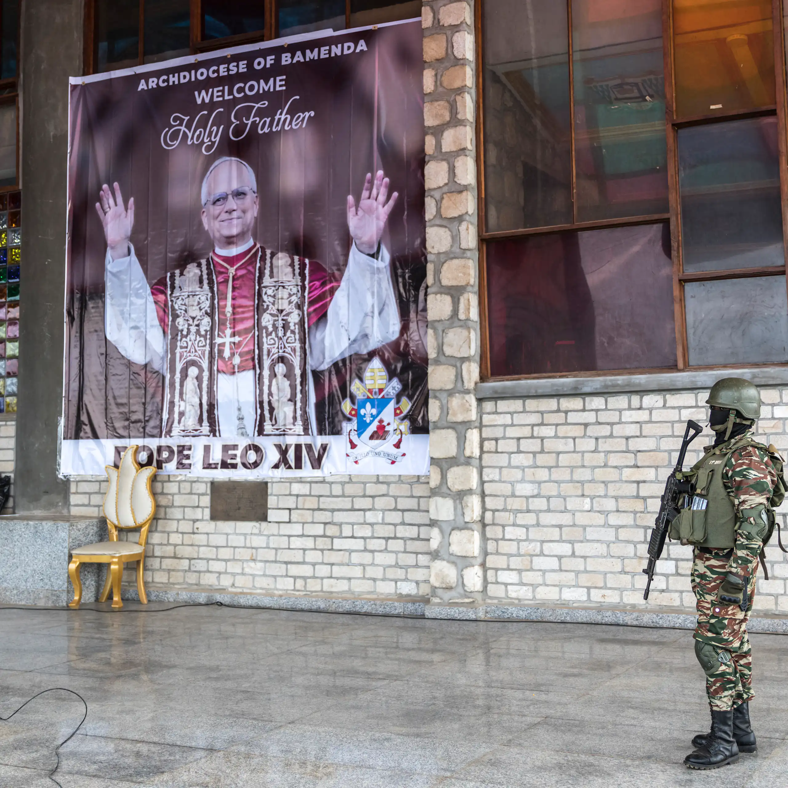Affiche de Léon XIV, un soldat camerounais en armes se tient devant.