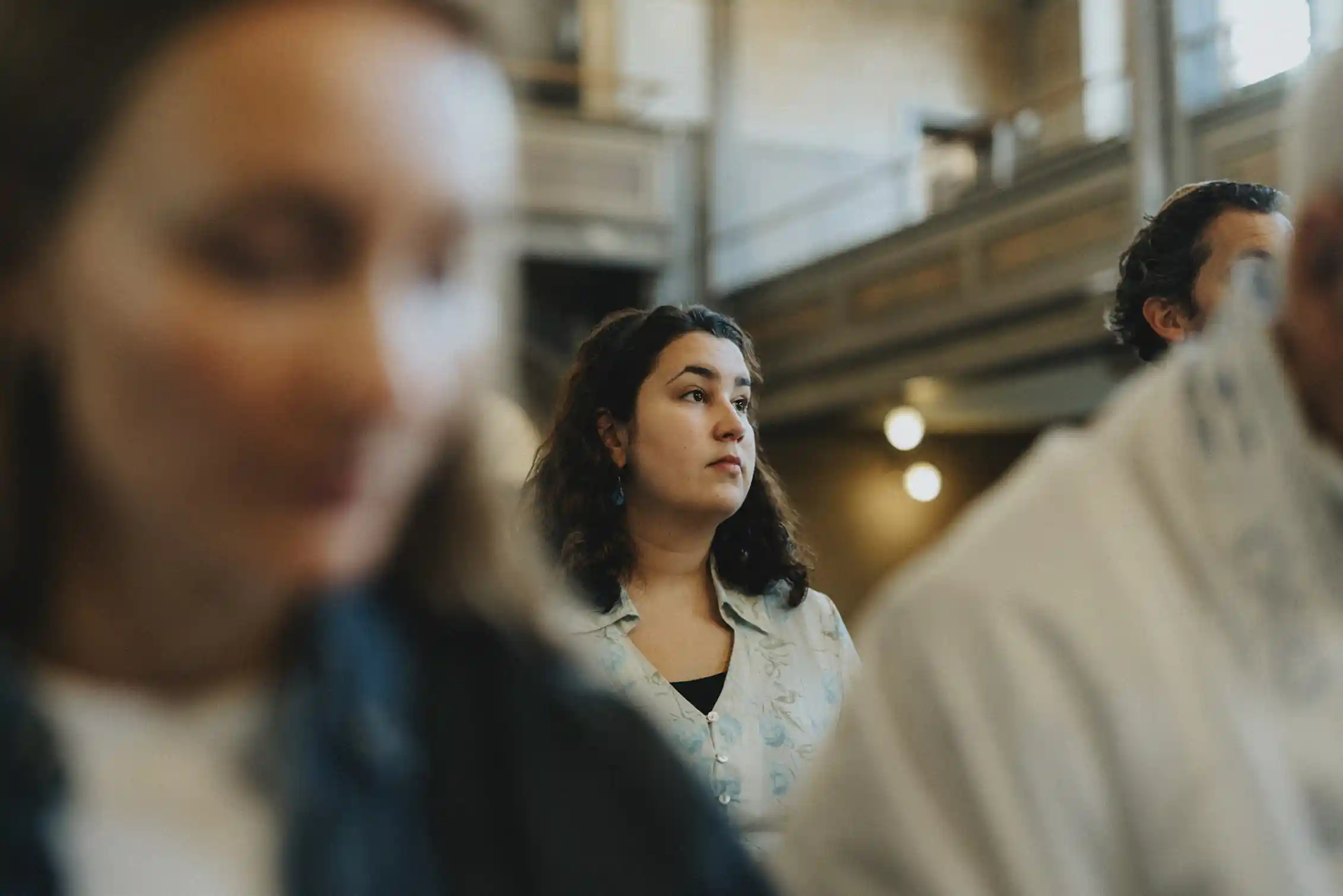 A woman stares into the distance as she stands amid other people in a sanctuary.