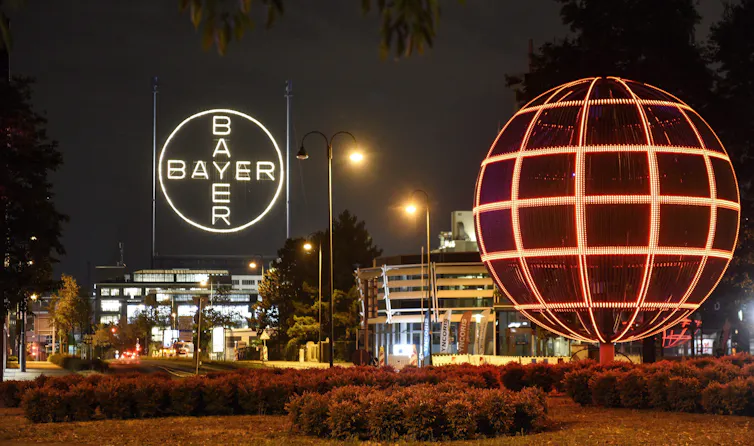 a corportate office building lit up at night with a sign reading Bayer