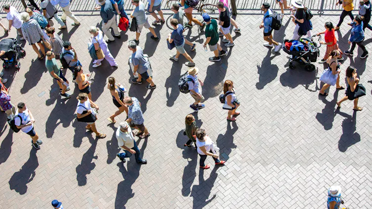 An aerial view of a crowd of people walking a city street