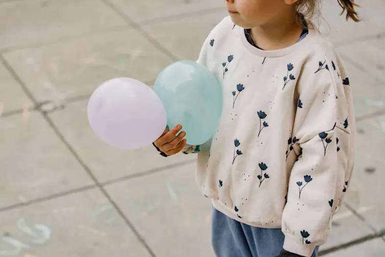 A girl holding two balloons.