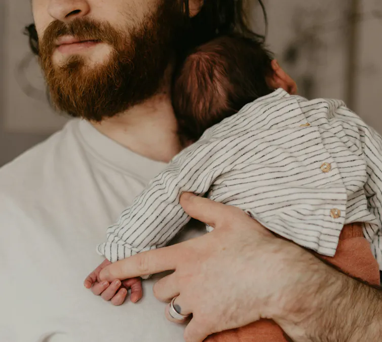 A bearded dad holding a tiny baby.