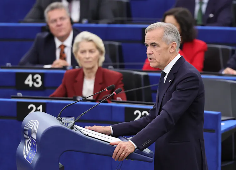 Canadian prime minister, Mark Carney, speaks from a podium. European commission president, Ursula von der Leyen looks on.