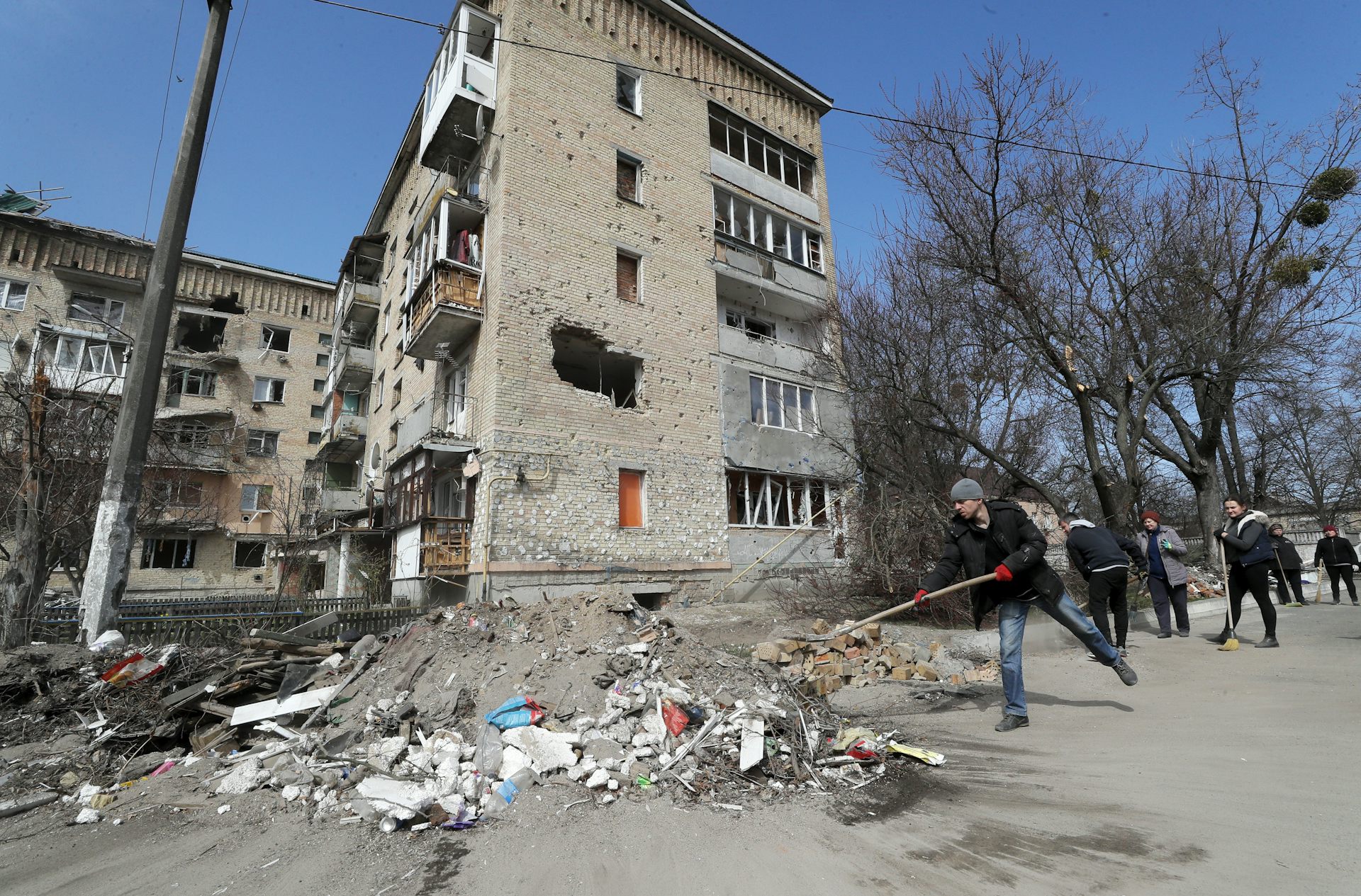 A group of residents clean debris from a damaged street in Makariv, Ukraine.