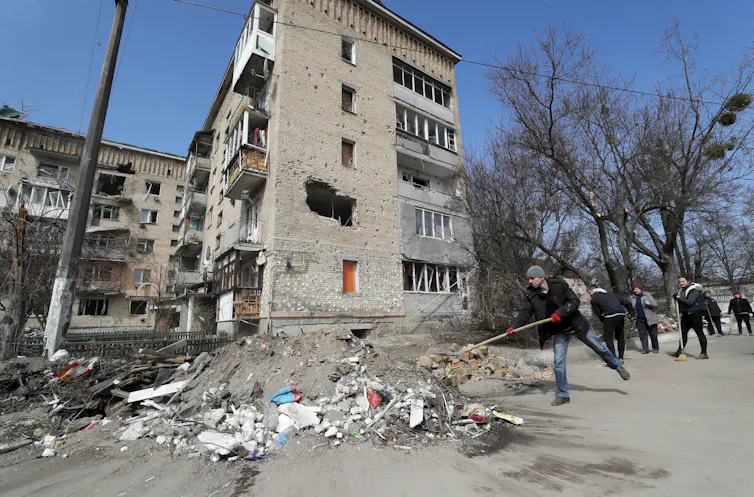 A group of residents clean debris from a damaged street in Makariv, Ukraine.