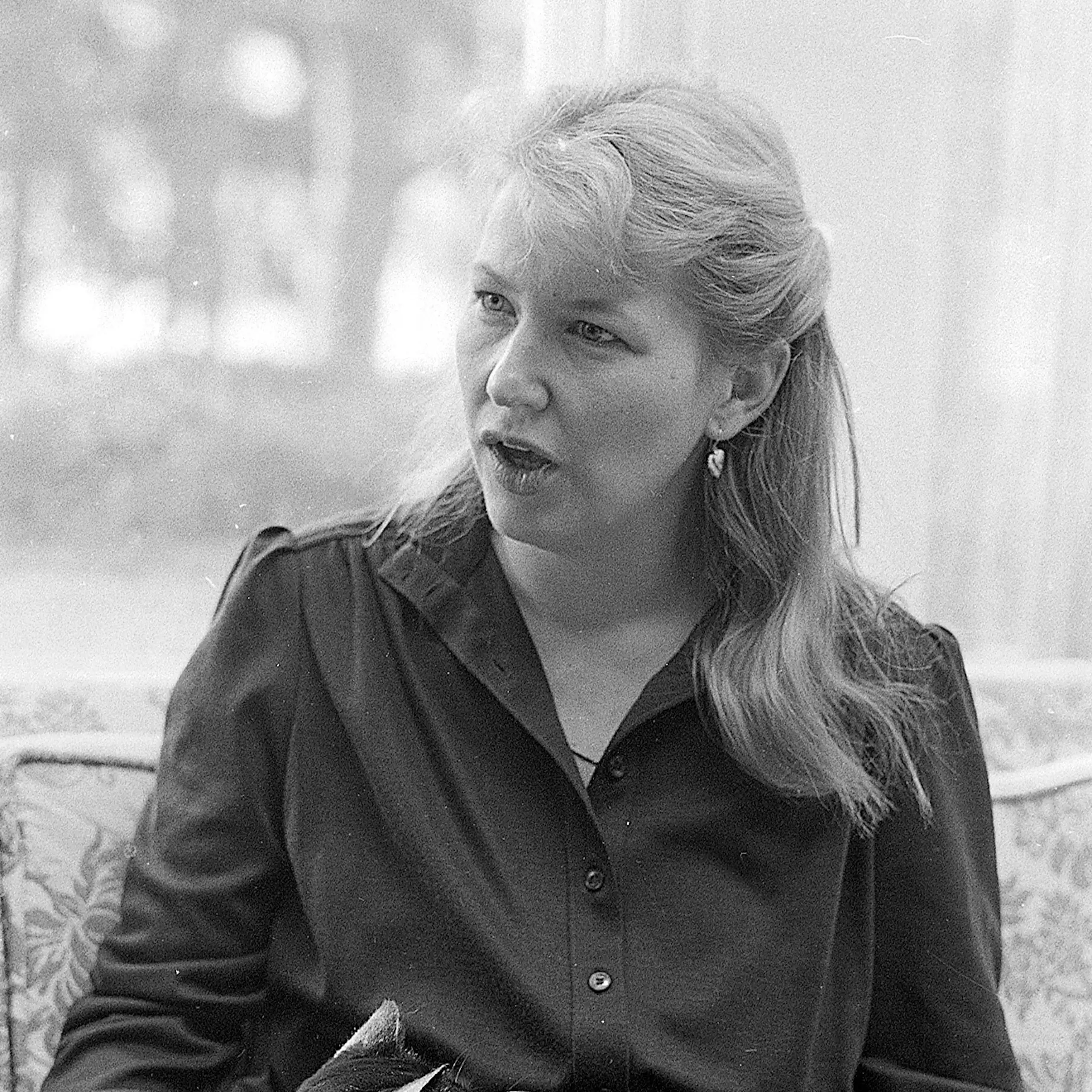 Black and white image of Annie Dillard sitting in a chair in 1983