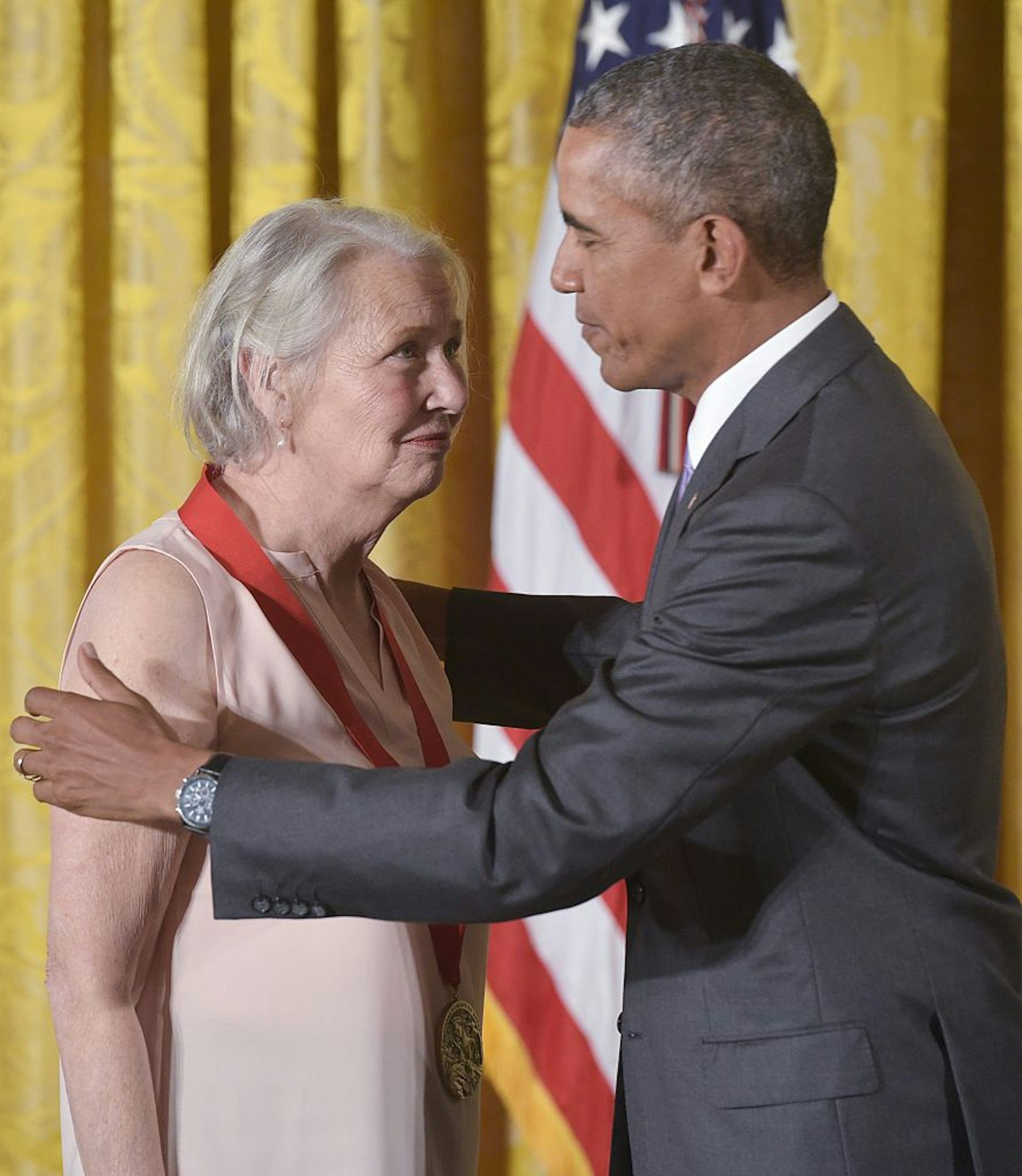 President Barack Obama with his hands on Annie Dillard's shoulders after placing a medal around her neck