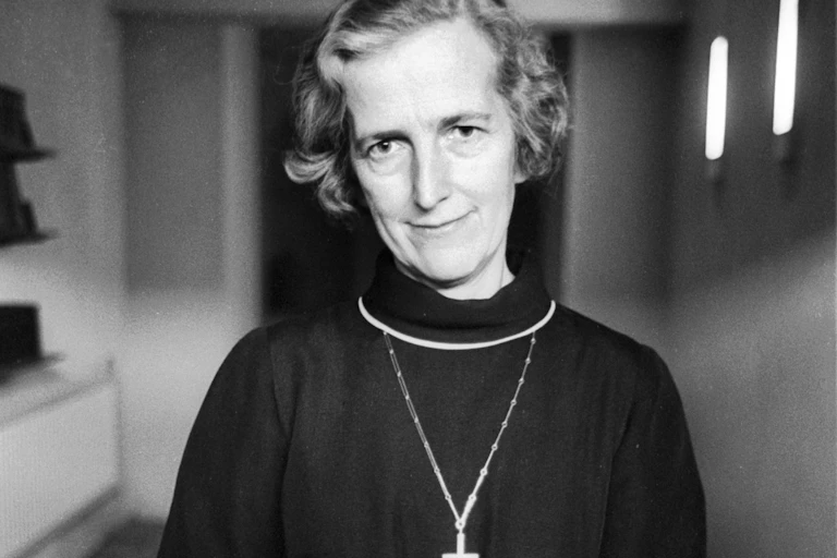 A black and white photograph of a woman in a priest's habit with a cross around her neck.