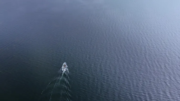 A small boat in a large expanse of water.