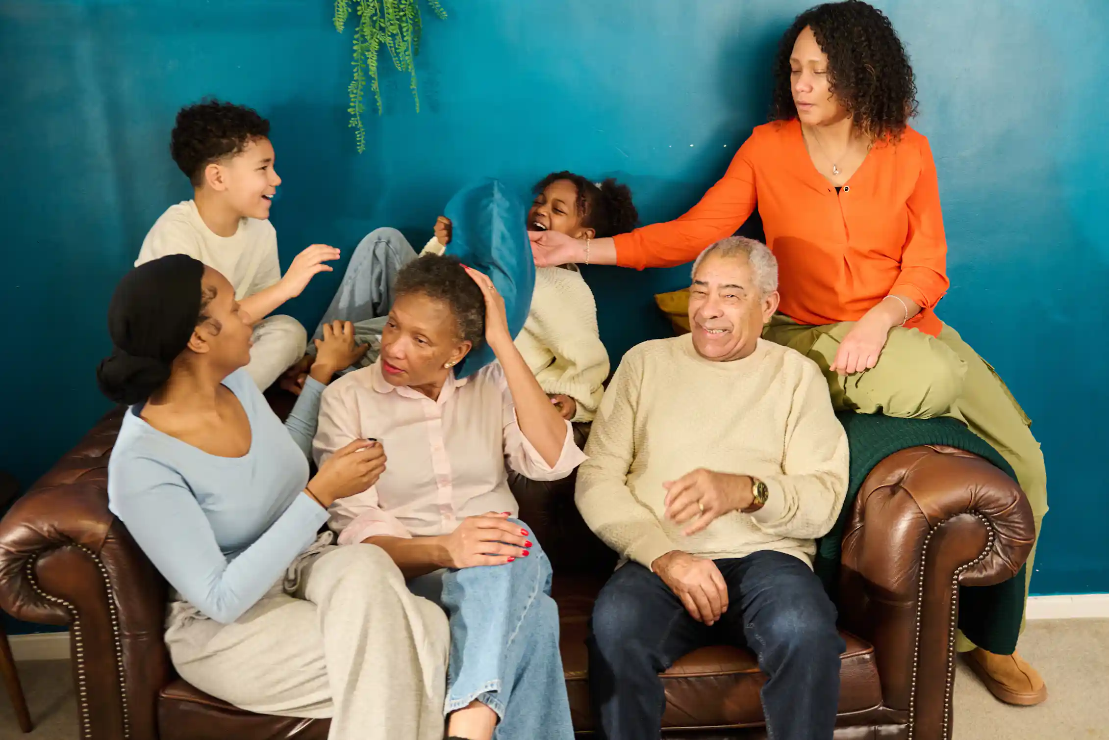 Multigenerational family laughing together on sofa at home.