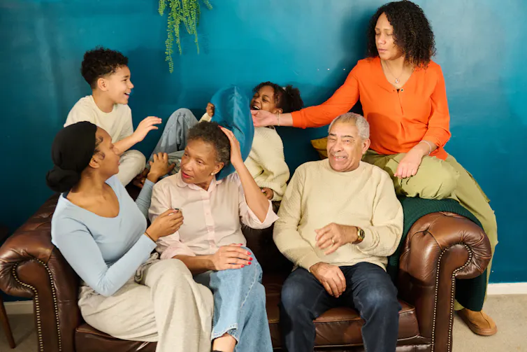 Multigenerational family laughing together on sofa at home.