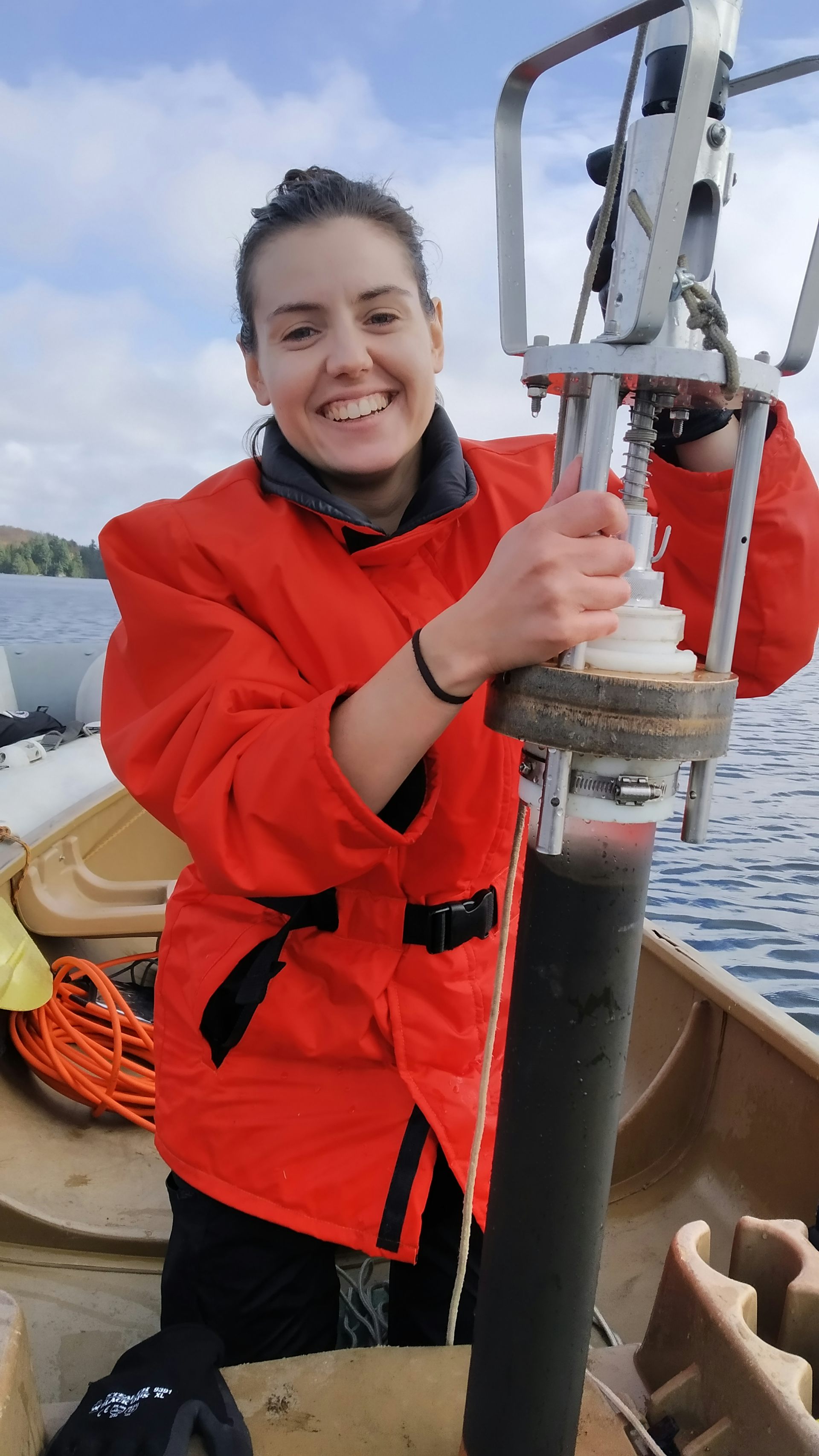 A researcher on a canoe holding equipment with a lake sediment core